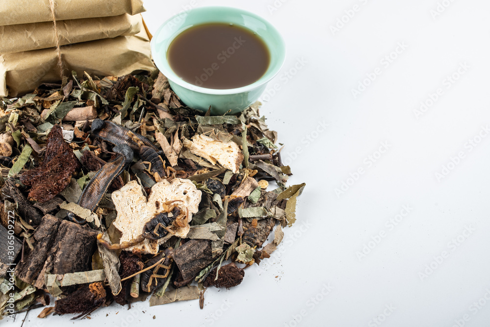 A pile of Chinese medicinal herbs and cooked soup on white background