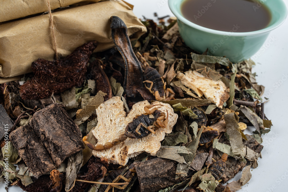 A pile of Chinese medicinal herbs and cooked soup on white background