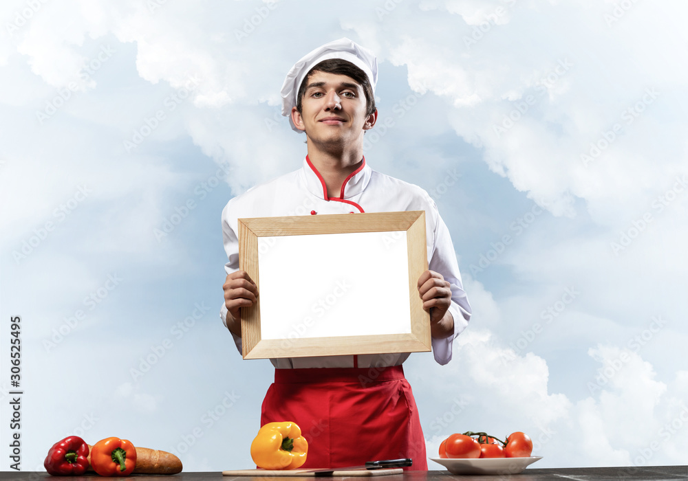 Young male chef standing near cooking table