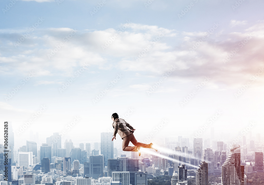 Businessman in suit and aviator hat flying in sky