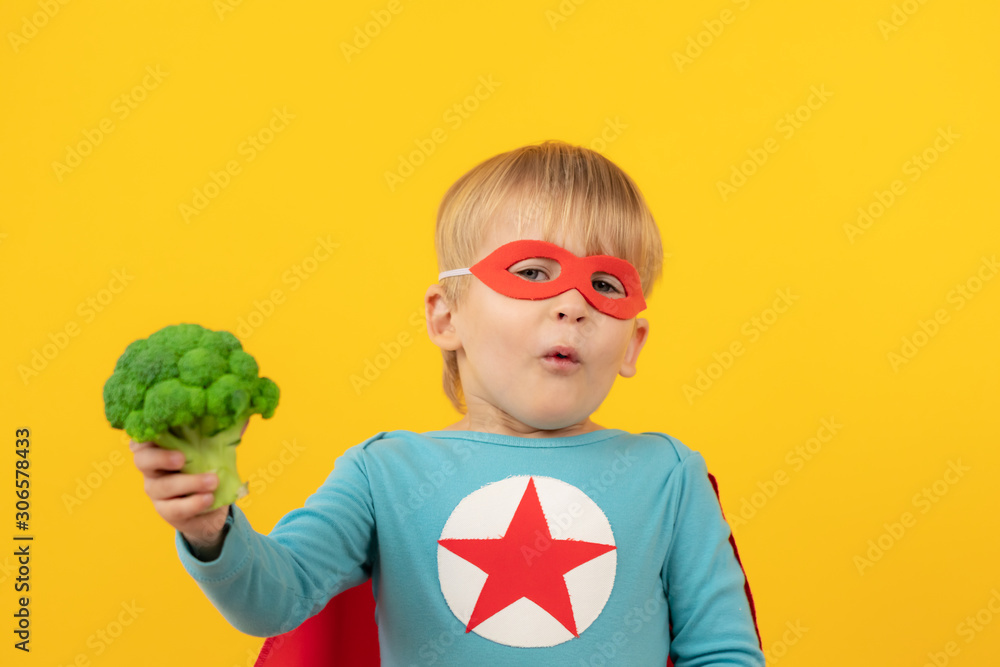 Superhero child holding broccoli