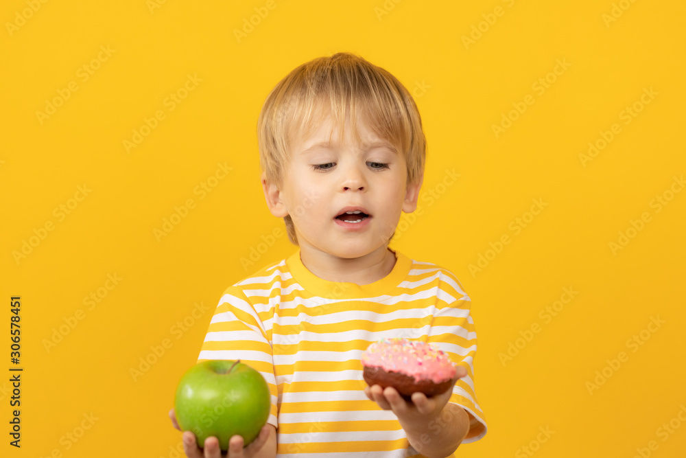 Happy child holding donut and apple