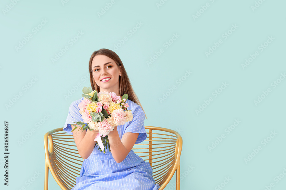 Beautiful young woman with bouquet of carnation flowers sitting in armchair on color background