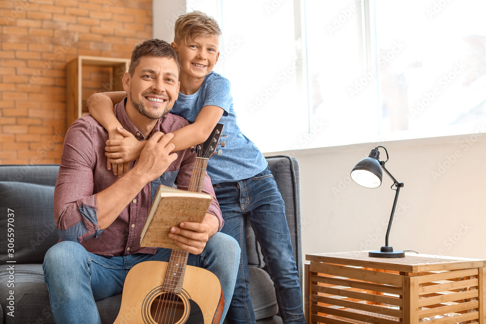 Father and his little son with guitar at home