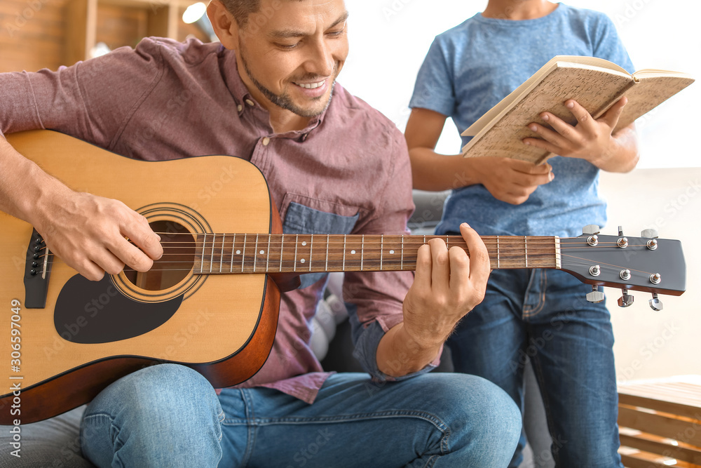 Father and his little son with guitar at home