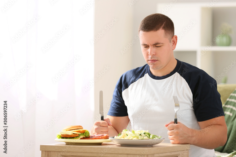 Overweight man choosing between healthy and unhealthy food at home