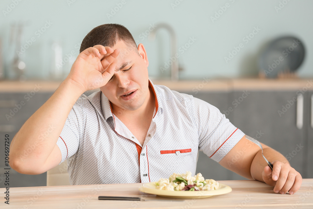 超重男子在厨房吃沙拉时哭泣。饮食概念