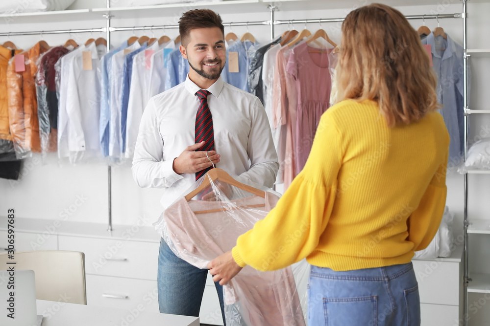 现代干洗店男员工向客户展示干净衣服