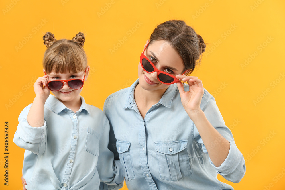 Portrait of stylish mother and daughter on color background