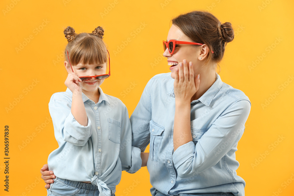 Portrait of stylish mother and daughter on color background