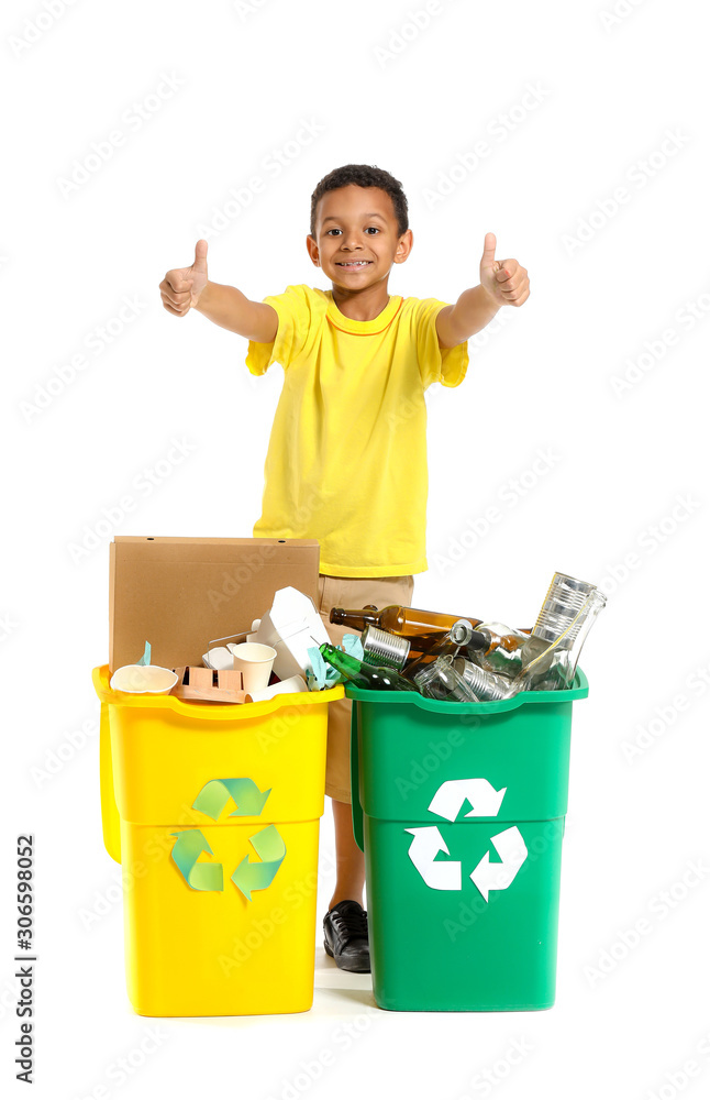 Little African-American boy showing thumb-up near containers with trash on white background. Concept