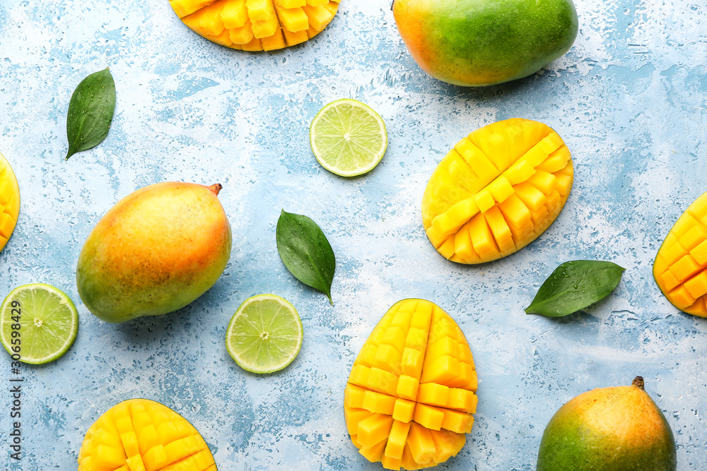 Sweet ripe mangoes and lime on color background