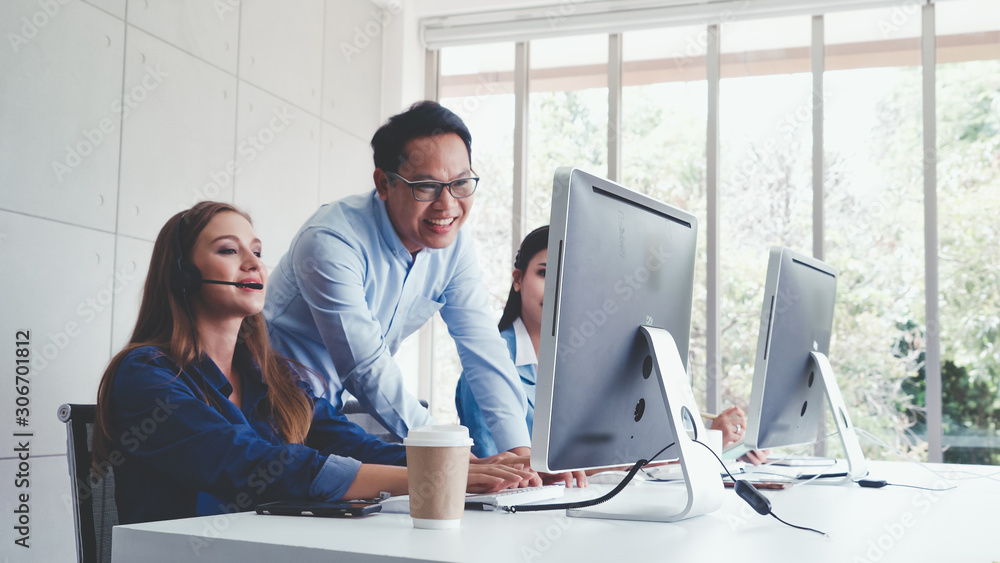 Customer support agent or call center with headset works on desktop computer while supporting the cu