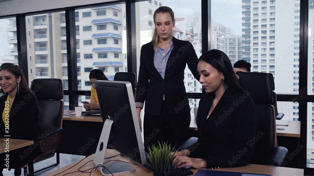 Young leader gives advice to young woman worker in modern office. Leadership and training concept.