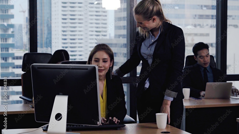 Young leader gives advice to young woman worker in modern office. Leadership and training concept.