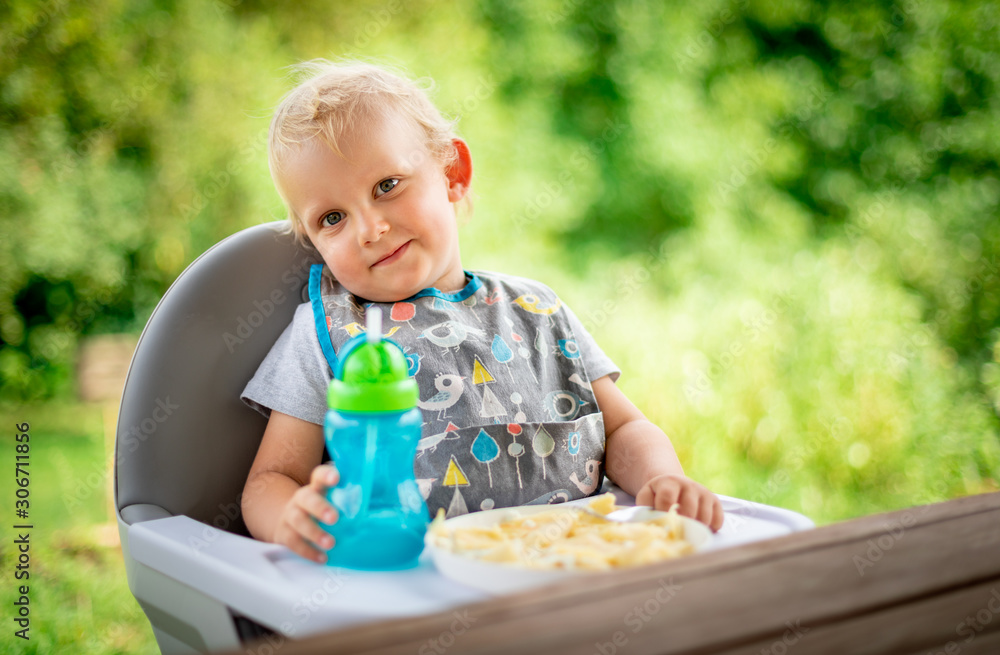 Cute baby sitting in high chair at the dinning table outdoor