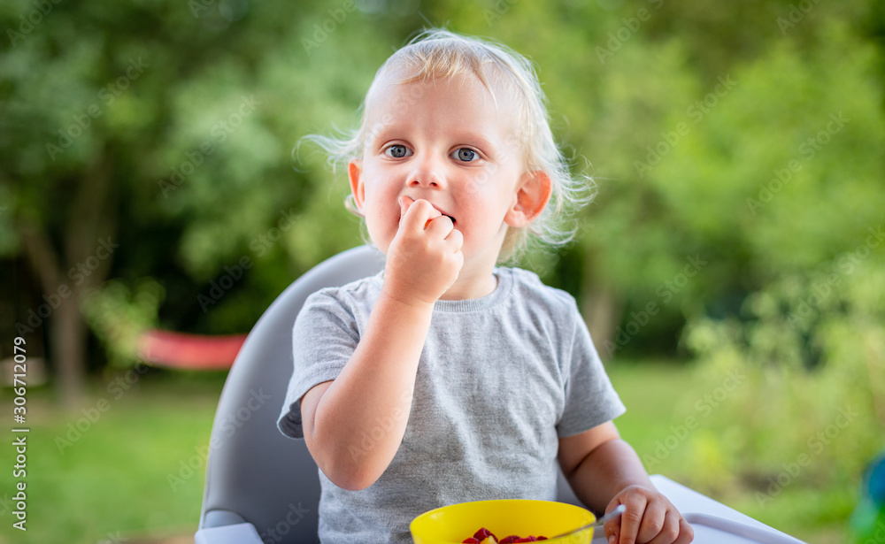 Cute happy baby boy eating outdoor and have fun