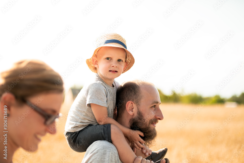 Happy family walking together with child on piggyback