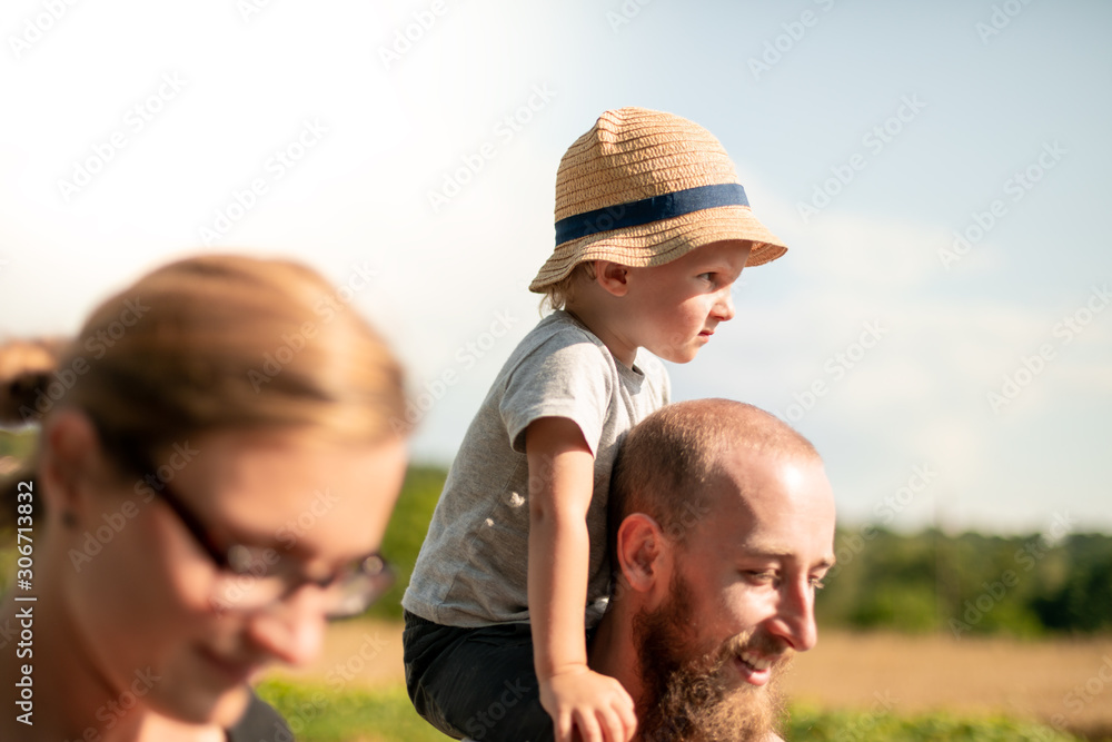 Happy family walking together with child on piggyback