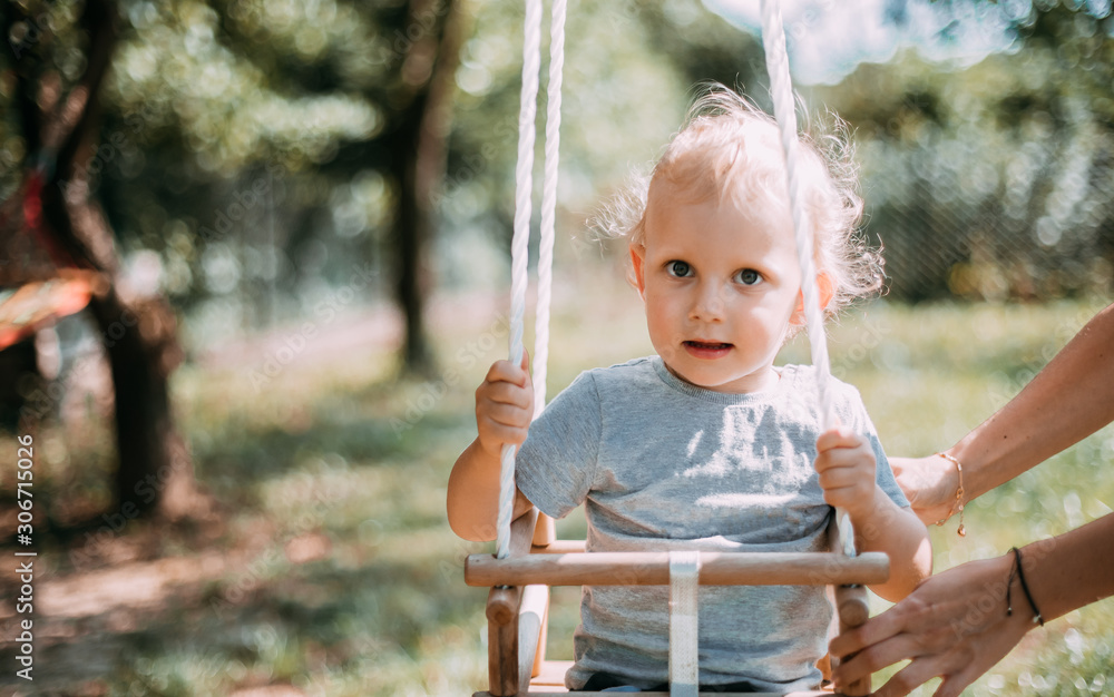 Little boy playing on swing in backyard at coutryside