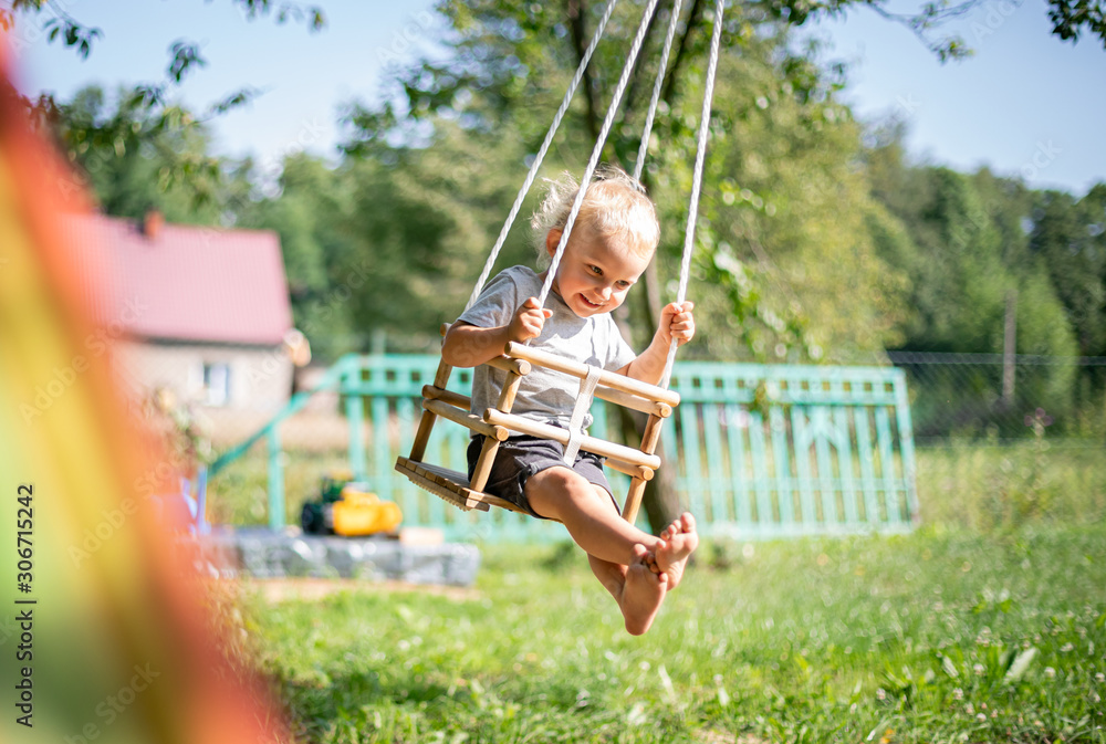 Little boy playing on swing in backyard at coutryside