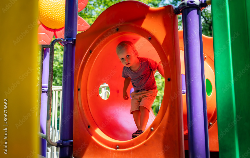 Little child boy playing on playground in the city park