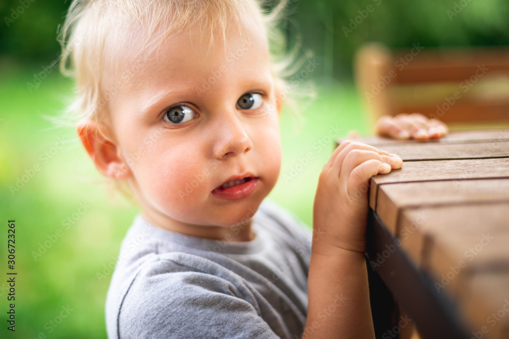 Portrait of little boy standing near table outdoor