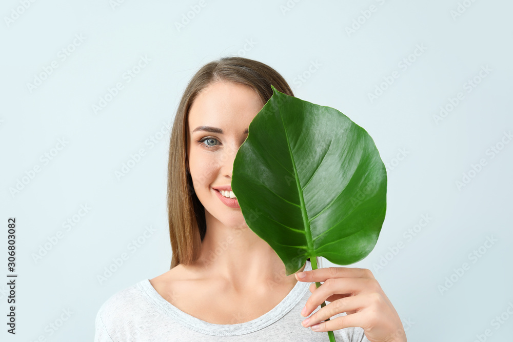 美丽的年轻女子，浅色背景为热带树叶