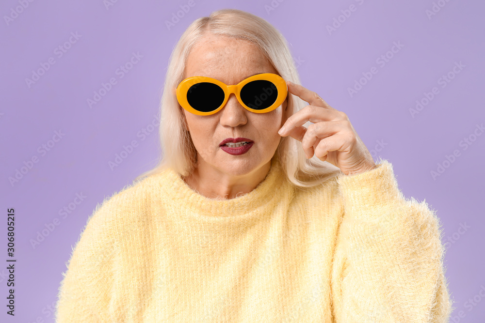 Fashionable mature woman on color background