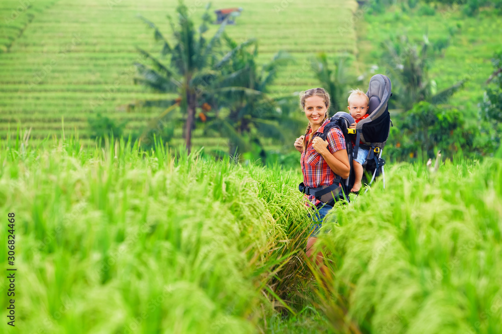 Nature walk in green rice terrace field. Happy mother hold little traveller in carrying backpack. Ba