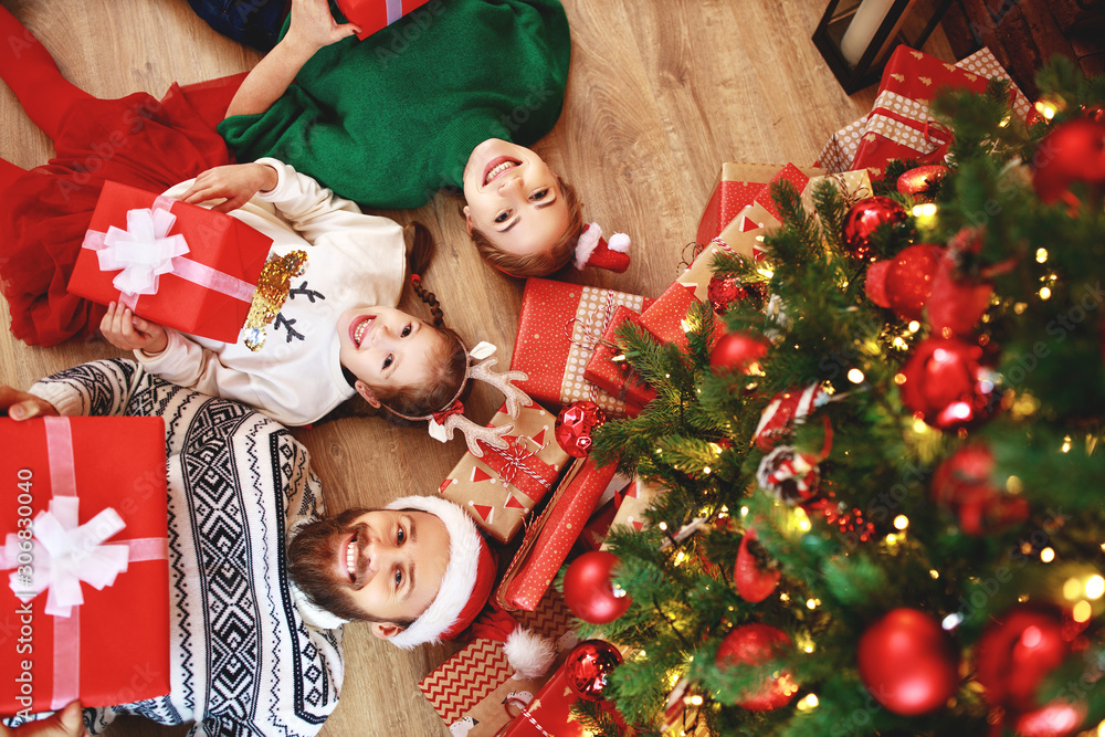 . happy family mother, father and child  with gifts near   Christmas tree at home.