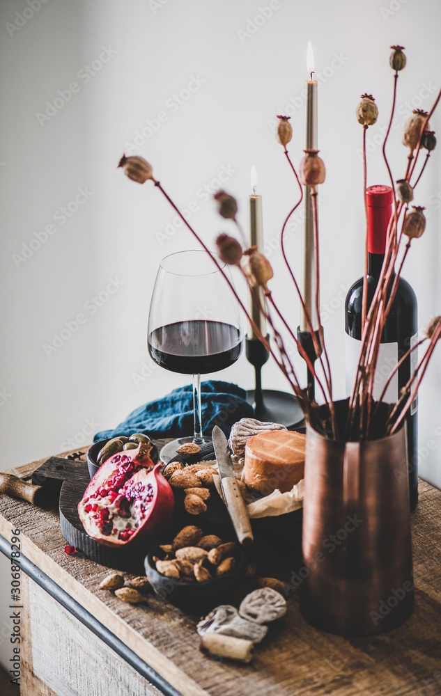 Wine and snack set. Glass and bottle of red wine, board with cheese, fruit, almonds and olives, cand