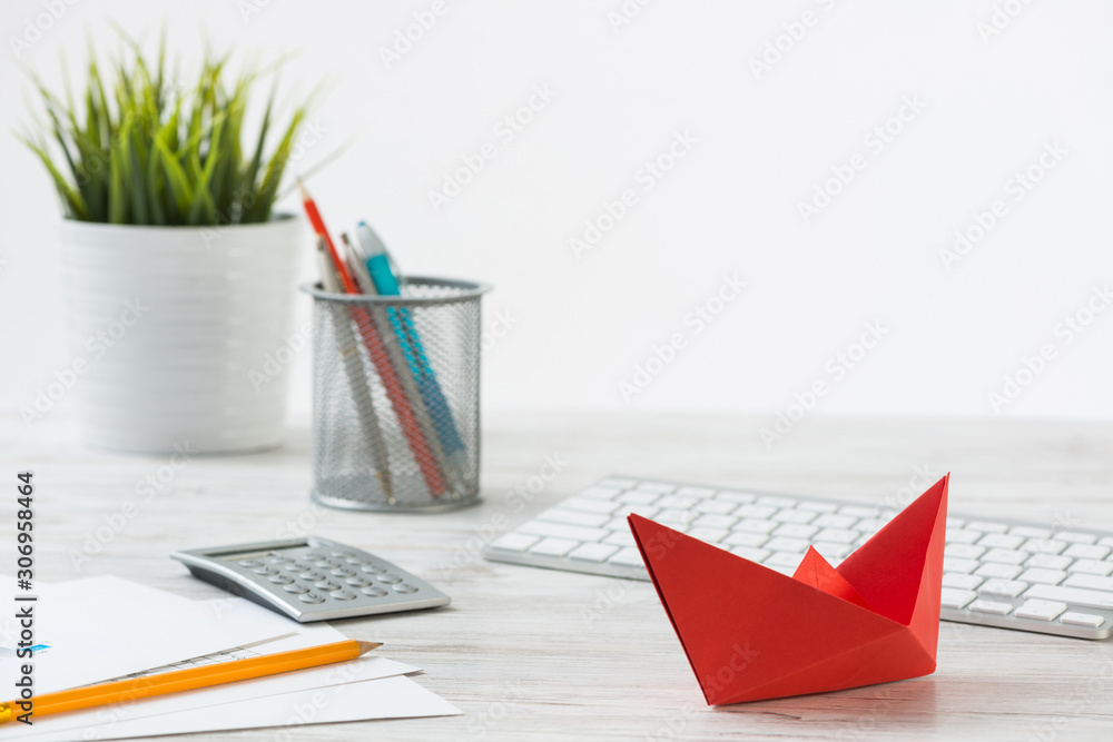 Wooden office desk with red origami boat