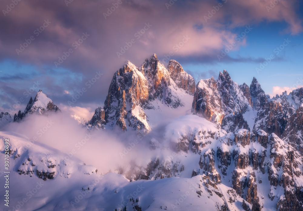 雾中雄伟的雪山山峰，日落时蓝天白云。冬季景观wi