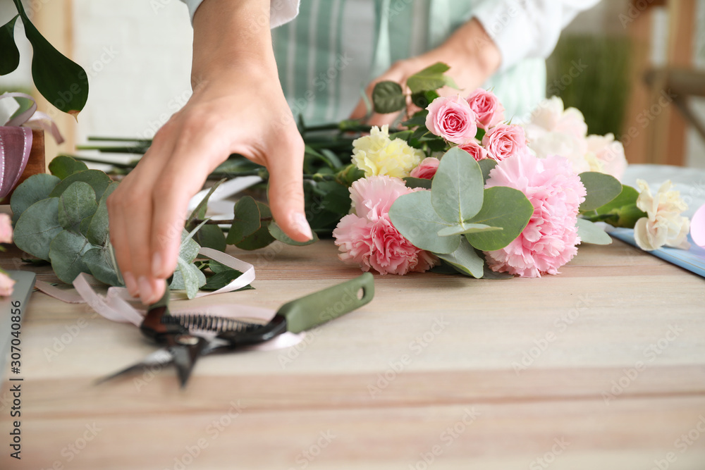 Female florist making beautiful bouquet in shop, closeup