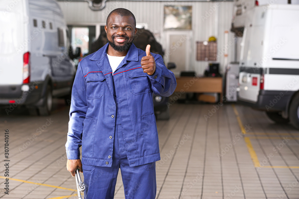 African-American mechanic showing thumb-up gesture in car service center