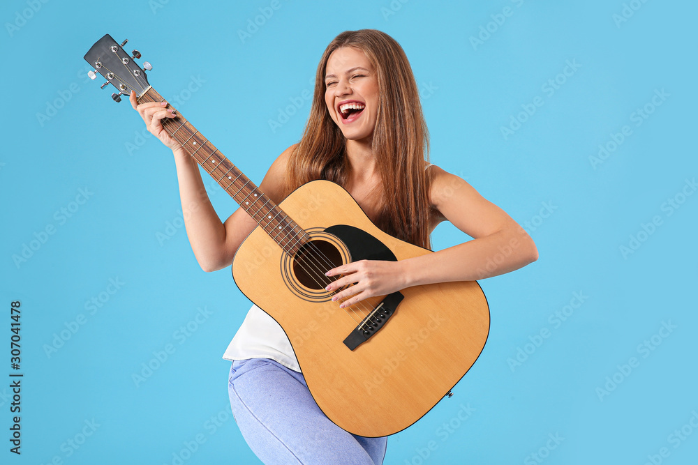 Beautiful young woman with guitar singing on color background