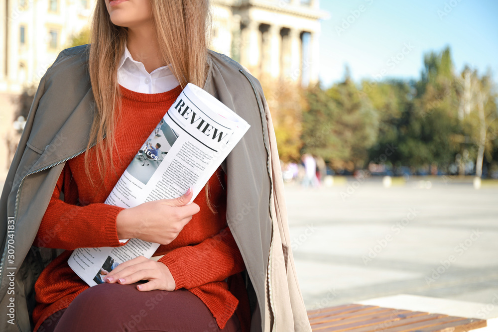 户外拿报纸的年轻女性