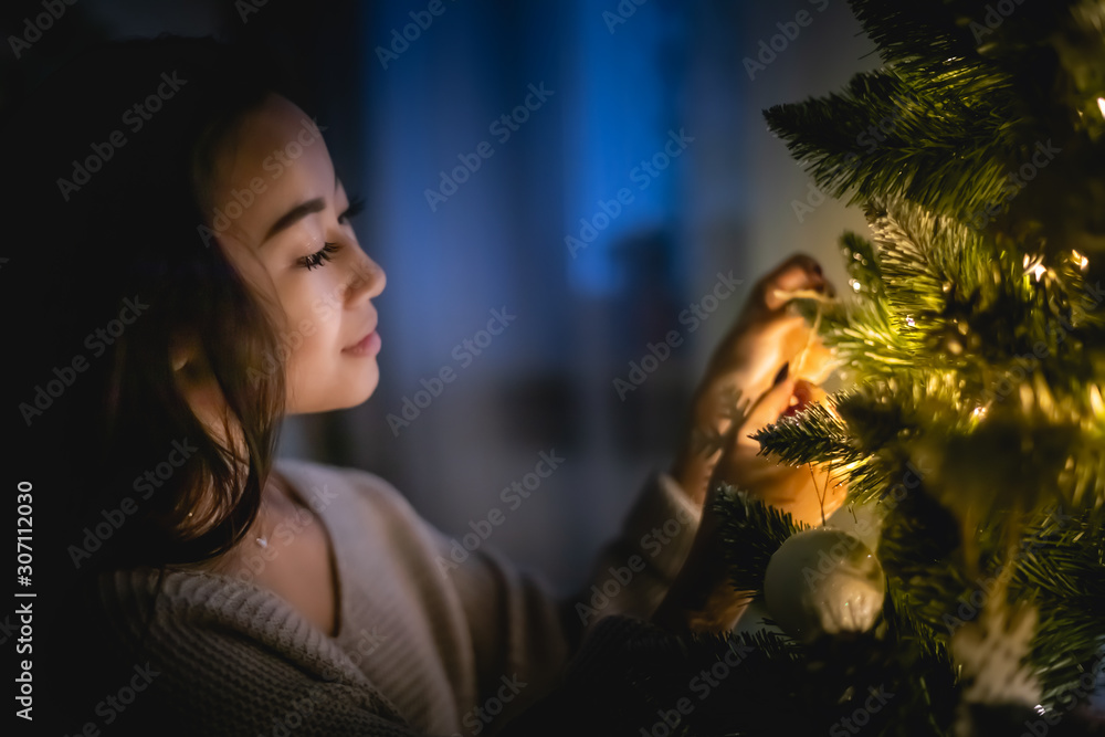 美丽的亚洲女孩在圣诞节晚上装饰家