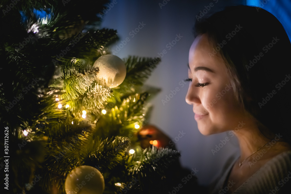 美丽的亚洲女人晚上在家里装饰圣诞树