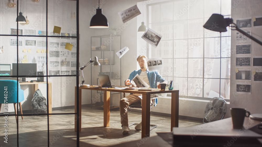 Frustrated and Tired Young Creative Designer Works on Laptop at His Desk, Threw Sheets with Concept 