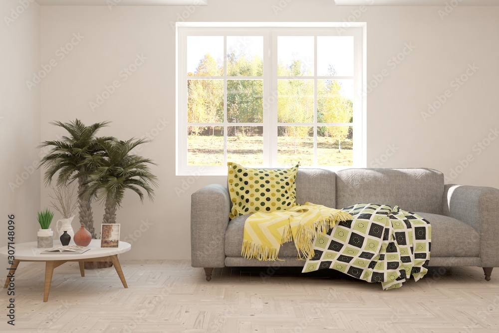 Stylish room in white color with sofa and autumn landscape in window. Scandinavian interior design. 