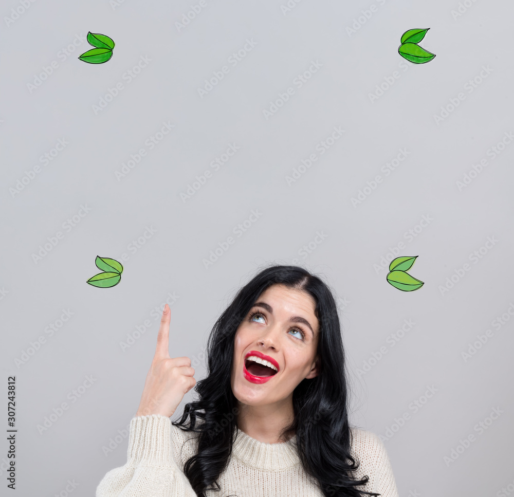 Green leaves with happy young woman on a gray background