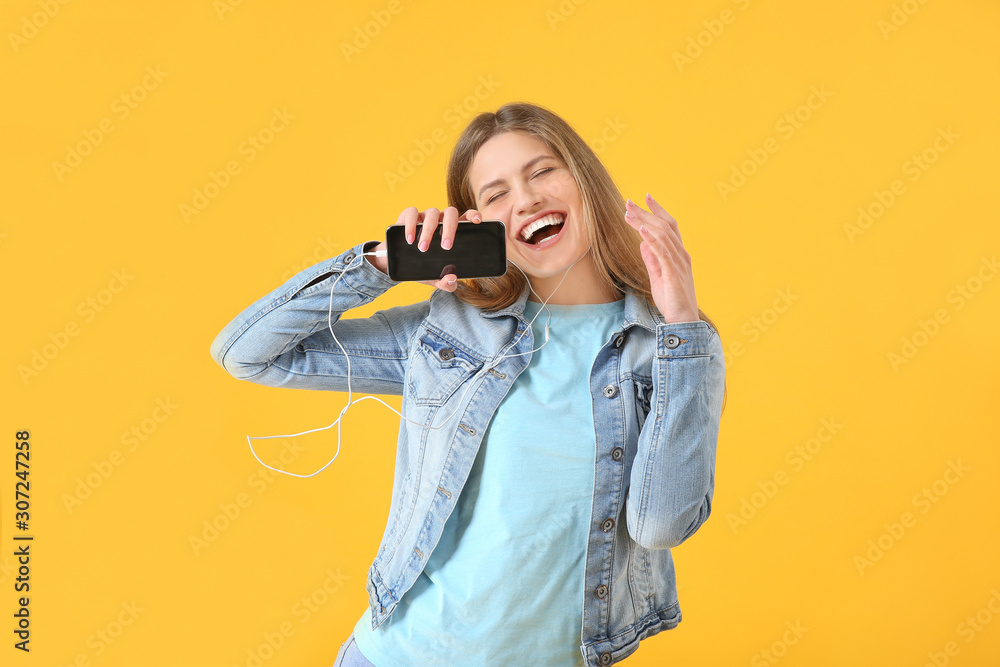 Beautiful young woman listening to music and singing on color background