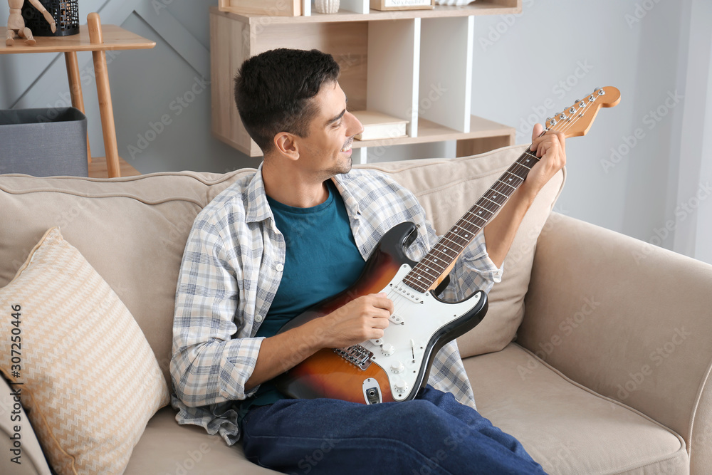 Handsome man playing guitar at home