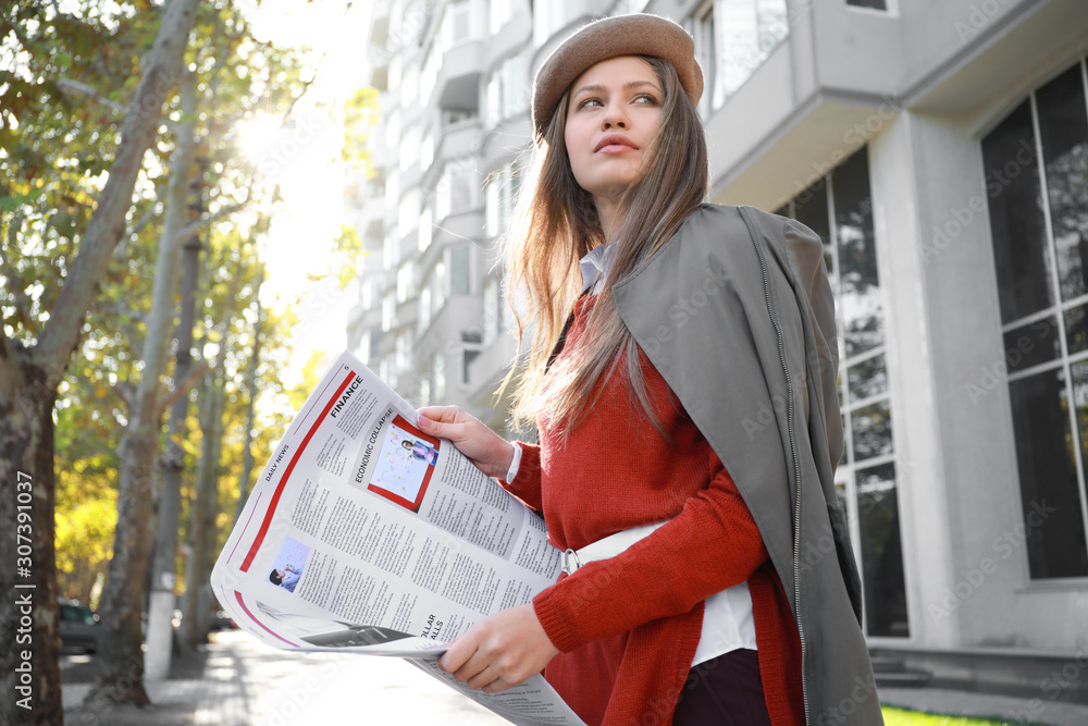 Young woman with newspaper outdoors