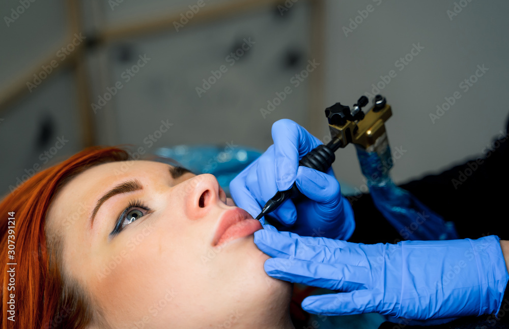 Cosmetologist making permanent makeup on womans face, cropped photo. Beauty concept. Closeup