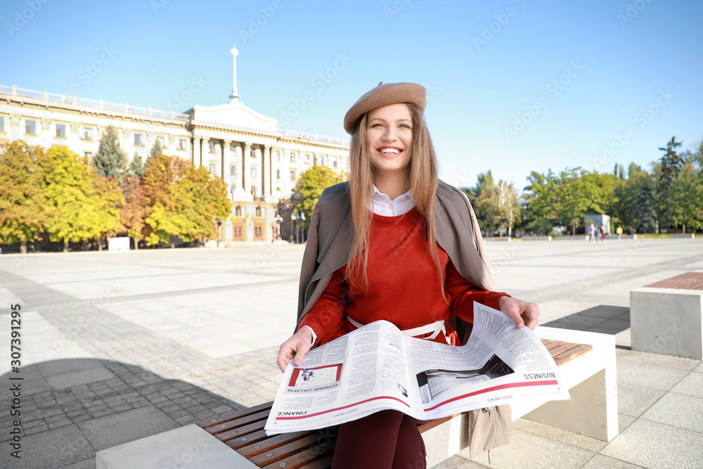 Young woman with newspaper outdoors