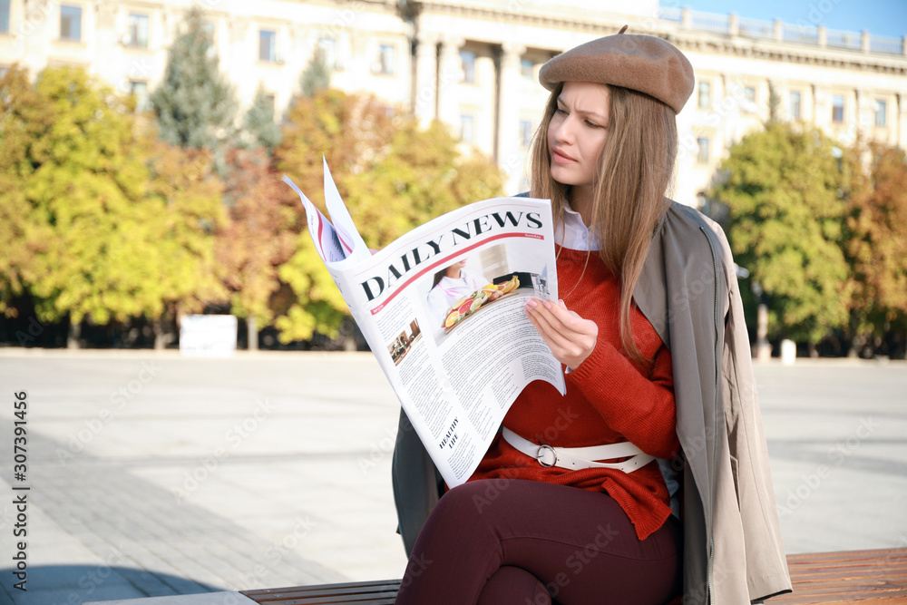 Young woman with newspaper outdoors