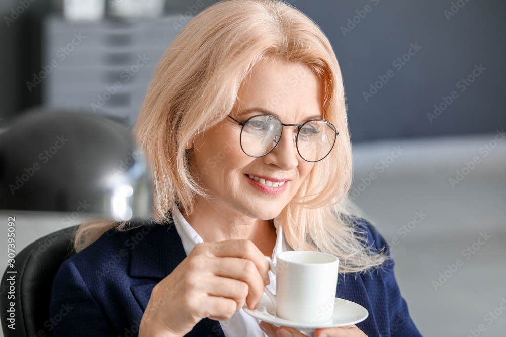 Mature businesswoman drinking coffee in office